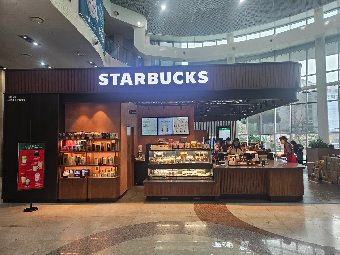 원목 캐노피 위에 STARBUCKS 조명 문자를 설치한 병원 로비 매장